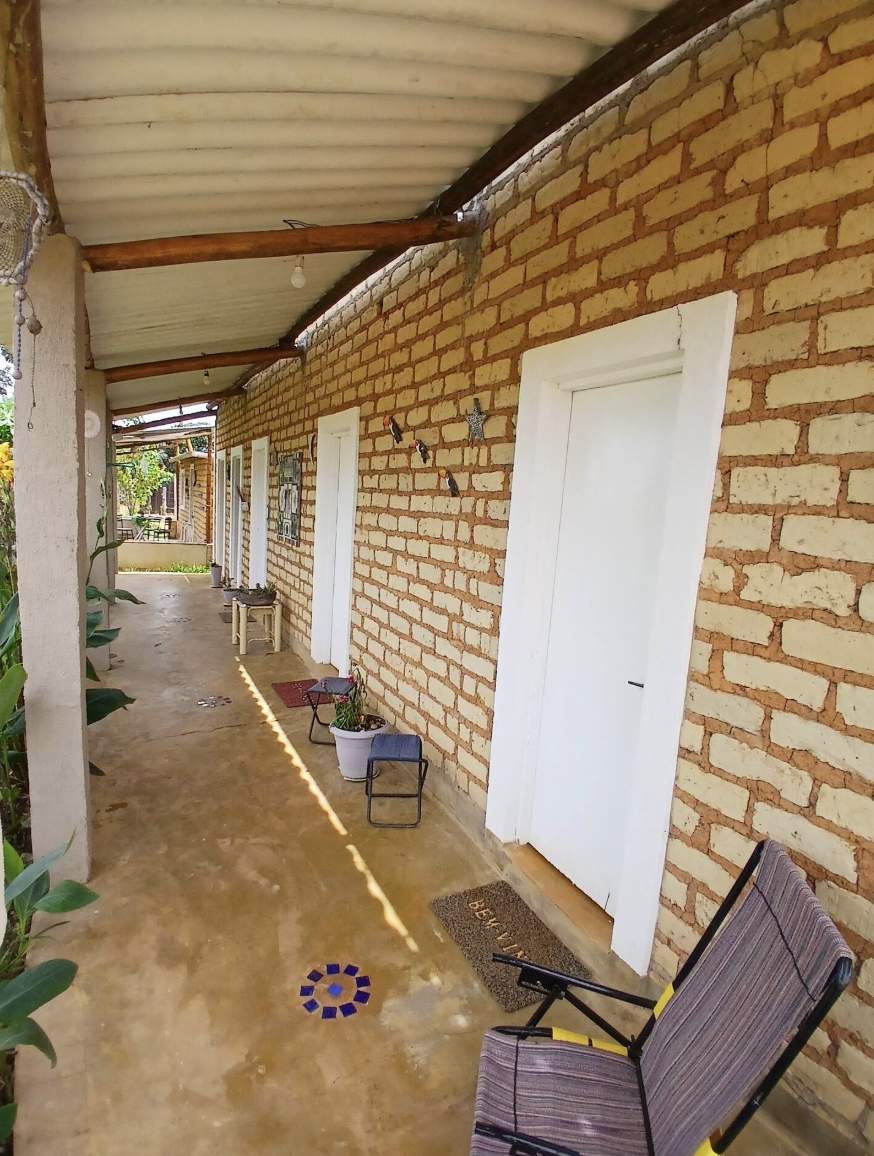 Varanda de tijolos com as portas brancas dos quartos do retiro