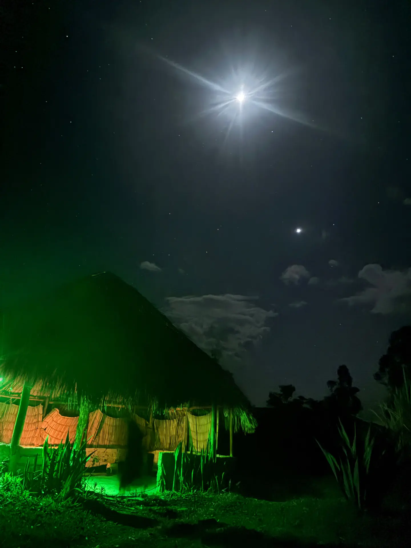 Casa de palha iluminada sob a lua e as estrelas durante a noite no retiro