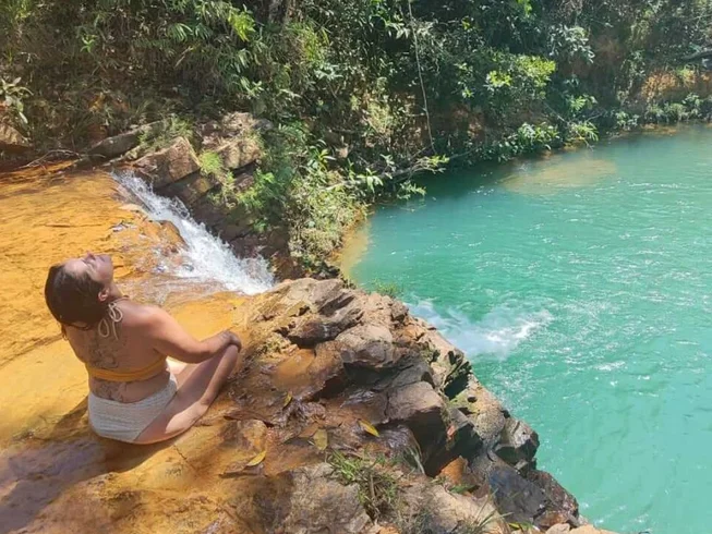Mulher em silêncio à beira de um poço de águas turquesa na Chapada dos Veadeiros