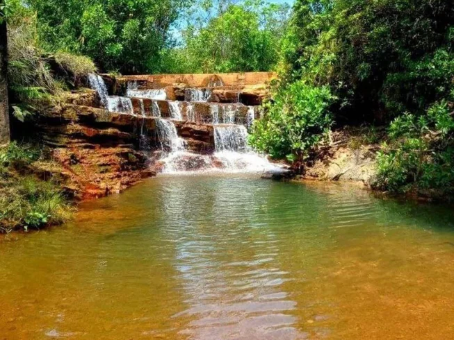 Cachoeira em degraus caindo em um poço de águas calmas cercado de mata