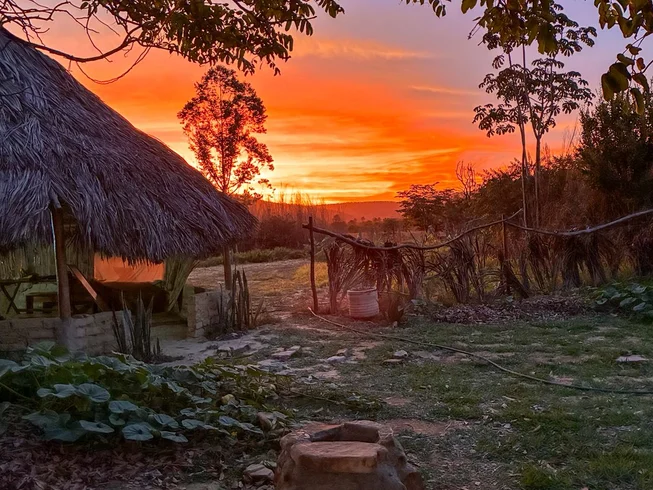 Pôr do sol alaranjado atrás da oca de palha do retiro